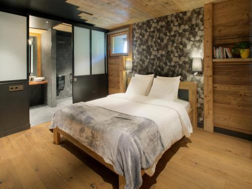 a bedroom with a large bed and a bathroom at Chalet 1703 - Open Living Hotel & Spa in Le Petit-Bornand-lès-Glières