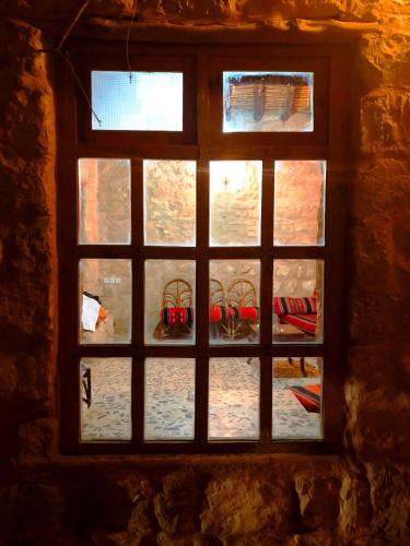 a window in a stone wall with chairs outside at The Orient Home in Wadi Musa