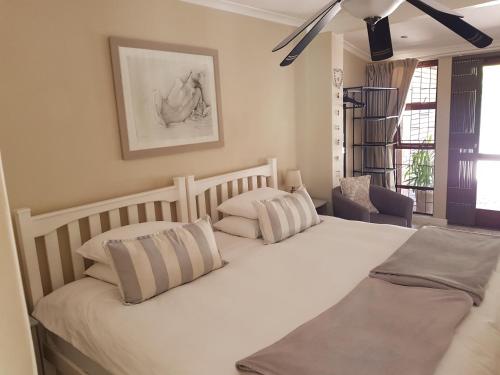 a bedroom with two beds and a chair at The Fairway in Cape Town