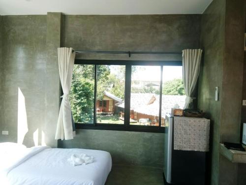 a bedroom with a bed and a large window at T&P at Pai in Pai