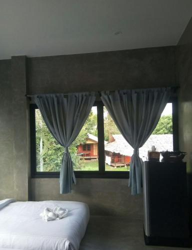 a bedroom with a bed and a window with curtains at T&P at Pai in Pai