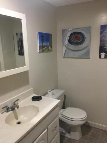 a bathroom with a sink and a toilet and paintings at Art Gallery Hostel in Whitefield