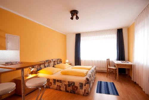 a bedroom with a bed and a desk and a window at Hotel Hottentotten in Regensburg