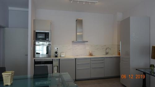 une cuisine équipée d'appareils en acier inoxydable et d'une table en verre dans l'établissement AU COEUR DES LICES *** CENTRE HISTORIQUE AVIGNON, à Avignon