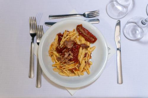 a plate of pasta with sausage and sauce on a table at Hotel Calanca in Marina di Camerota