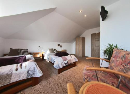 a attic bedroom with two beds and a chair at Dom Lwowski in Sanok