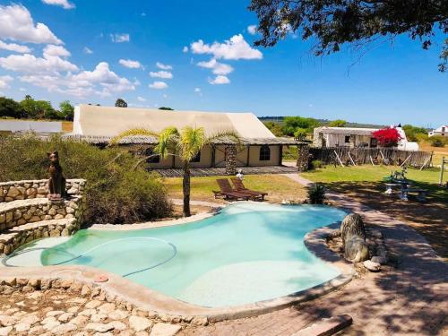 a swimming pool in a yard with a house at Thali Thali Game Lodge in Langebaan