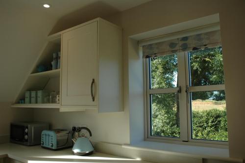 a kitchen with white cabinets and a window at The Starting Gate, Bruton in Bruton