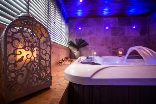 La salle de bains est pourvue d'une baignoire avec des lumières violettes. dans l'établissement Charme et Spa dans un domaine d'élevage, à Sennevières