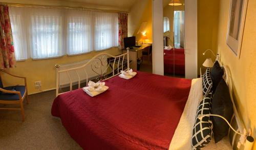 a bedroom with a red bed with two towels on it at Amadeus Boutique Hotel Deutscher Hof in Georgenthal