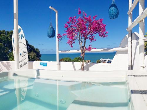 una villa con piscina y un árbol con flores púrpuras en Pousada Mediterrânea, en Pipa