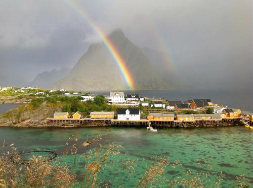 a rainbow over a city with a town and a harbor at Sakrisøy Rorbuer in Reine