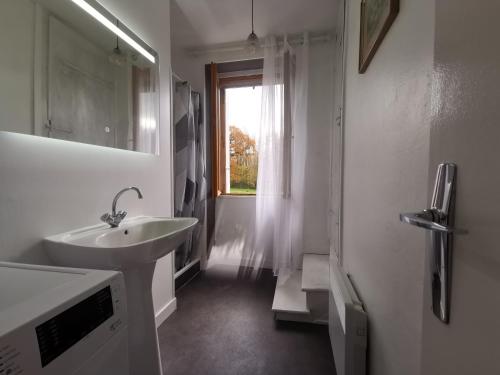 une salle de bain blanche avec un lavabo et une fenêtre dans l'établissement Three rooms above a bar Résistance meuseum, à Saint-Sébastien