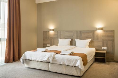 a bedroom with a large bed with two towels on it at Семеен Хотел Естило in Dimitrovgrad