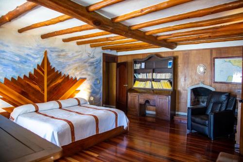 ein Schlafzimmer mit einem Bett, einem Stuhl und einem Kamin in der Unterkunft Tzampoc Resort in Santa Catarina Palopó
