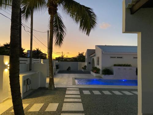 a villa with a swimming pool and a palm tree at Movida Inn Aruba in Palm-Eagle Beach