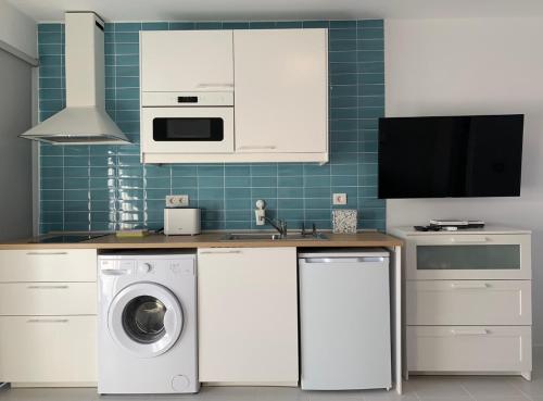 a kitchen with a washing machine and a tv at Puerto del Carmen Luxury Apartment in Tías
