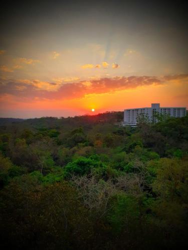 a sunset over a field with trees and buildings at Prime Hotel Águas da Serra in Rio Quente
