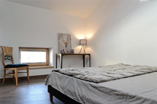 a bedroom with a bed and a chair and a window at Apartment El Molin - Alpe Cermis Dolomites in Cavalese