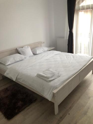 a large white bed with white sheets and pillows at Deluxe Villa with BBQ in Şelimbăr