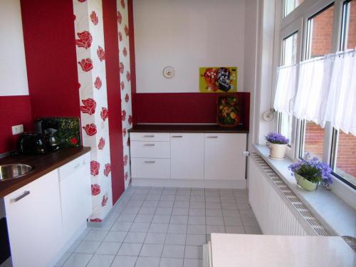 a kitchen with white cabinets and red walls at Ferienwohnung Markert in Blankenburg