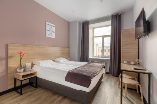 a bedroom with a bed and a desk and a window at Nomera na Goncharnoy in Saint Petersburg