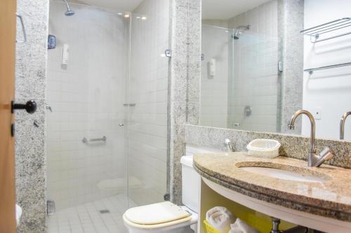 uma casa de banho com um chuveiro, um lavatório e um WC. em Muro Alto Marulhos em Porto de Galinhas