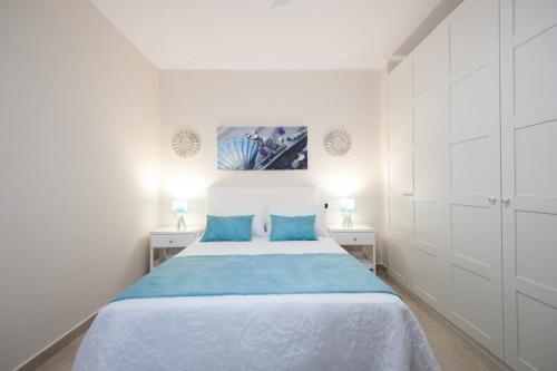 una camera bianca con un grande letto con cuscini blu di El faro a Las Playitas