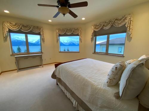 a bedroom with a bed with a ceiling fan and windows at Seward Front Row Townhouse in Seward