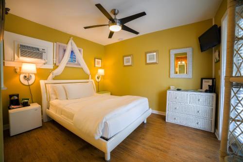a bedroom with a white bed and yellow walls at Seascape Tropical Inn in Key West