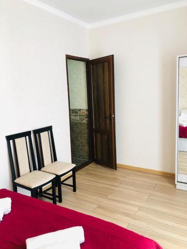 a room with a bed and two chairs and a door at Wander Kazbegi Hotel in Stepantsminda