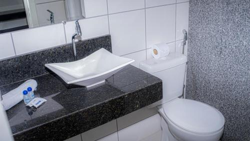 a bathroom with a white toilet and a sink at Sueds Segundo Sol in Santa Cruz Cabrália