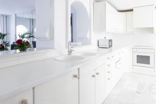 a white kitchen with white cabinets and a sink at Hotel Suites Albayzin Del Mar in Almuñécar