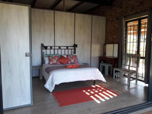 1 dormitorio con cama y alfombra roja en RoamRooiberg, en Robertson