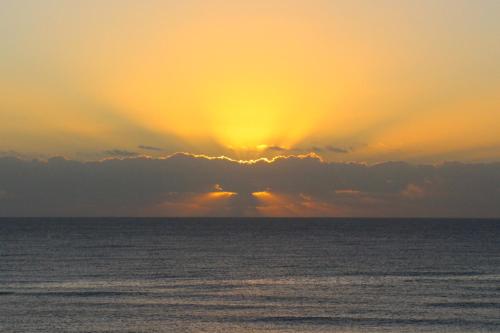a sunset over the ocean with the sun hiding behind clouds at Beautiful & Cozy Studio in Akumal Paradise-Wifi, AC in Akumal