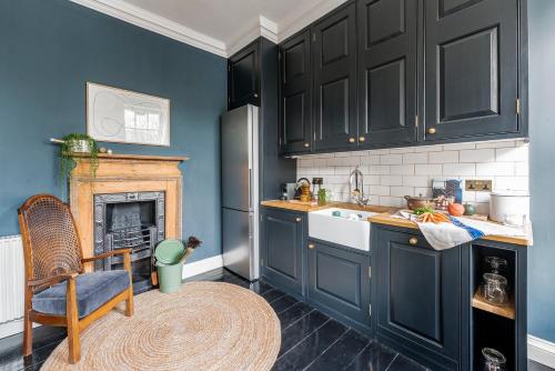 a kitchen with black cabinets and a fireplace at Superior Stays Rosewell House - Bath City Centre in Bath