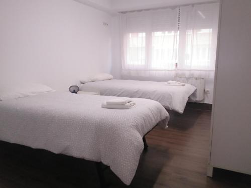 2 camas en una habitación blanca con sábanas blancas en Apartamento familiar Torrelavega en Torrelavega