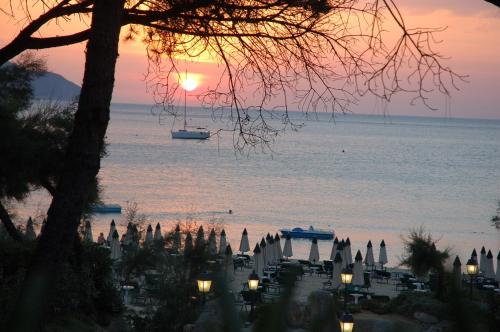 a sunset over a city with a boat in the water at Hotel Villa Ombrosa in Portoferraio