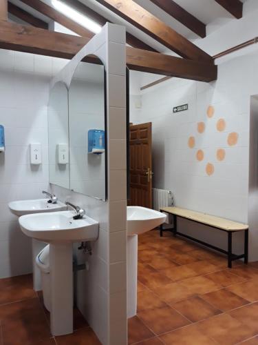 a bathroom with two sinks and a mirror and a bench at Albergue La Vargona in Camaleño