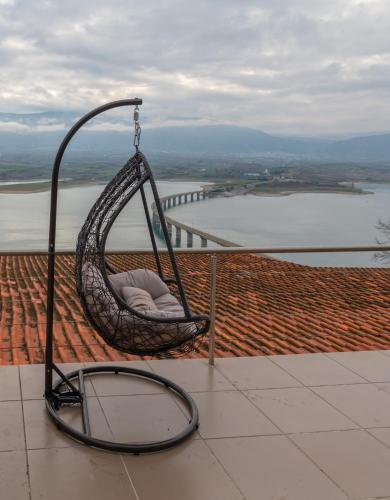 a hanging chair on a balcony with a view of the water at Vai Guesthouse Neraida in Neráïdha