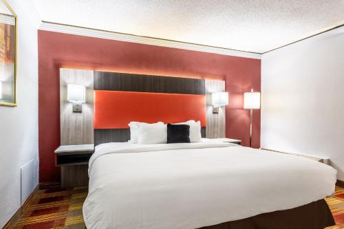 a large bed in a room with a red wall at Countryside Suites Kansas City Independence I-70 East Sports Complex Hotel in Independence