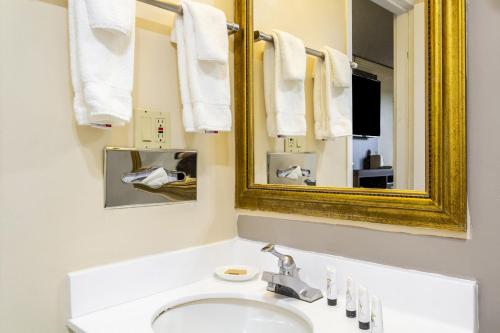 a bathroom with a sink and a mirror and towels at Countryside Suites Kansas City Independence I-70 East Sports Complex Hotel in Independence