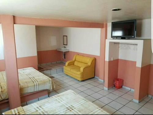 een kamer met een gele stoel en een tv bij Hotel Plaza in San Martín Texmelucan de Labastida