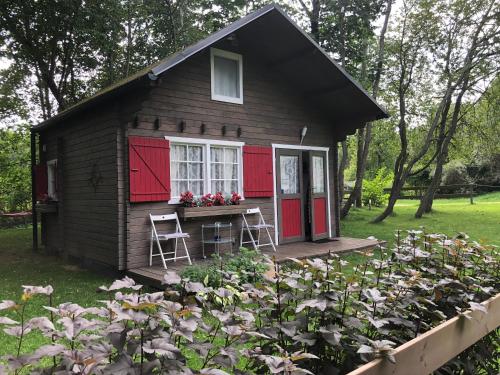 mały domek z czerwonymi drzwiami i ogrodem z kwiatami w obiekcie Summerhome w mieście Skulte