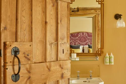een badkamer met een houten wand met een wastafel en een spiegel bij Crown and Anchor in Marlborough