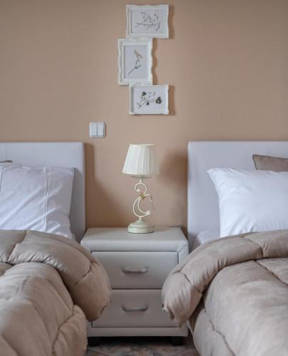 a bedroom with two beds and a table with a lamp at Vai Guesthouse Neraida in Neráïdha