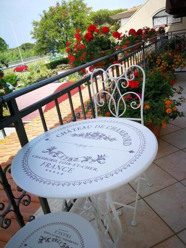 a white table and chairs on a balcony with flowers at Hotel La Rosa Dei Venti in Albinia