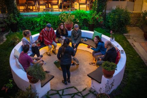 a group of people sitting around a table in a garden at Home Garden Hotel in Cusco