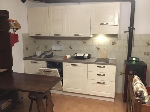 uma cozinha com armários brancos e uma mesa de madeira em Appartamento arredato con angolo cottura em Argentera