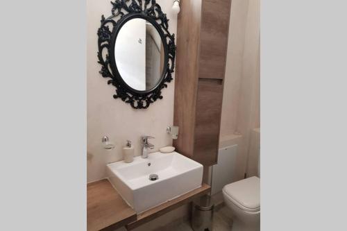 een badkamer met een witte wastafel en een spiegel bij Kyparissos blue stonehouse in Álika